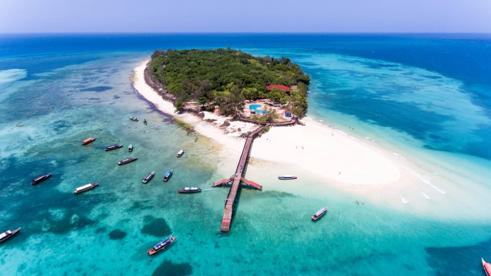 Aerial view of a tropical island, turquoise lagoon, white sand, pier, and boats — Indian Ocean island hopping